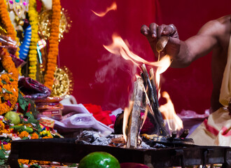 hand of a priest worshiping hindu god with fire and yagna ritual by adding fuel in flame