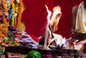 hand of a priest worshiping hindu god with fire and yagna ritual by adding fuel ghee in flame