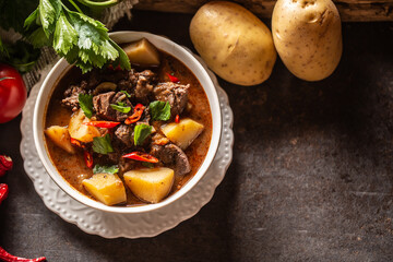 Bowl of goulash with meat, potatoes, chillies and parsley