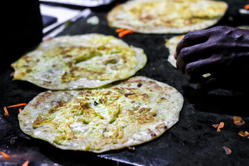 making of egg roll on a hot frying pan with oil and paratha and salad