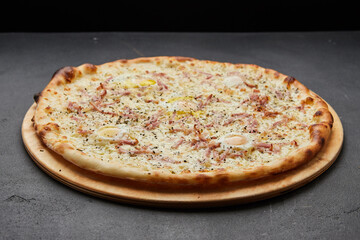 Delicious Italian Pizza Carbonara with Bacon, eggs and mozzarella cheese on dark background