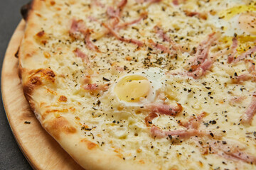 Delicious Italian Pizza Carbonara with Bacon, eggs and mozzarella cheese on dark background