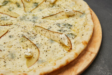 Delicious Italian Pizza with four cheeses and pear on dark background