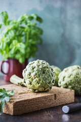 fresh ripe organic artichokes on dark rustic wooden background 