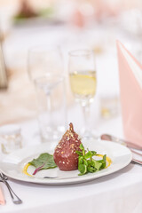 Glazed roasted pears with nut sprinkled on top on a festive table