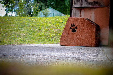 Dog kennel by the driveway with lawn and greenhouse in the background