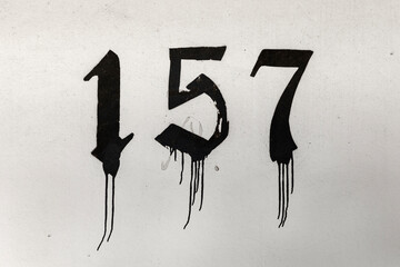 number 157 painted in old letter with black paint at a wall