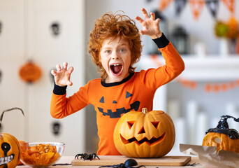 Happy redheaded boy in  costume with  pumpkin Jack o lantern   making scary faces  during a Halloween celebration.