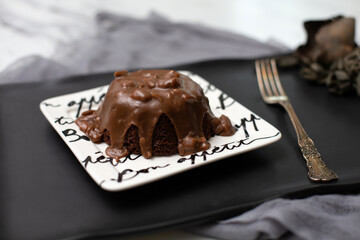 Close Up of Chocolate Cake with Chocolate Frosting with Nuts on Bon Appetite Plate on Black Tray