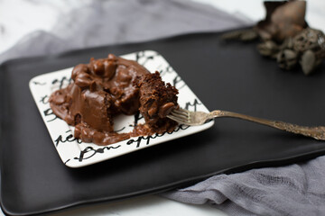 Close Up of Chocolate Cake with Chocolate Frosting with Nuts on Bon Appetite Plate on Black Tray, One Bite on Fork