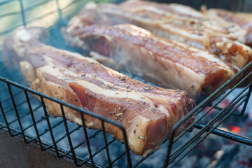 Barbecue pork spare ribs cooking on a grill outdoors in summer
