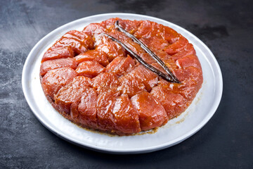 Traditional French tarte tatin with apples and vanilla offered as close-up on a modern Nordic design plate with rustic background