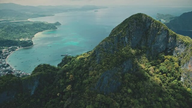 Ocean harbor town cityscape at mountain peak with green tropic forest. Many buildings at sea bay with boats, ships. Aerial of greenery trees at mountainous island Palawan, El Nido, Philippines, Asia.