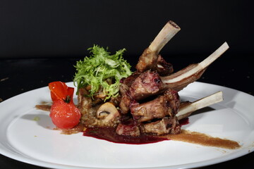 Lamb rack with couscous and sauce on a dark background
