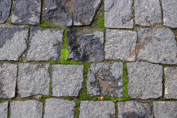 Granite paving stone background of the sidewalk. Abstract background of an old cobblestone street close-up