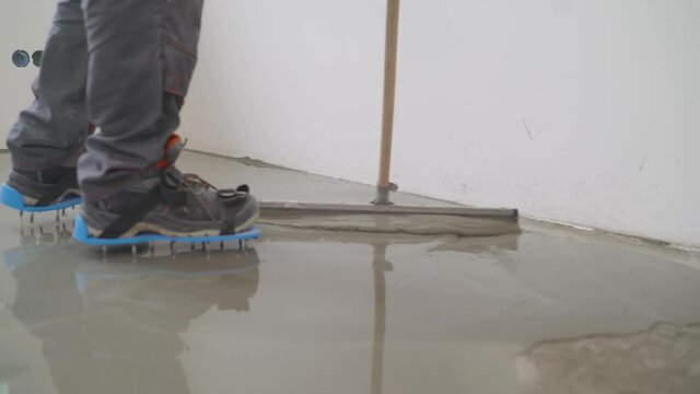 A worker rolls out the liquid floor with a trowel. Squeegee for distributing the mixture. The worker levels the liquid floor. Finishing works - Needle roller for bulk floor