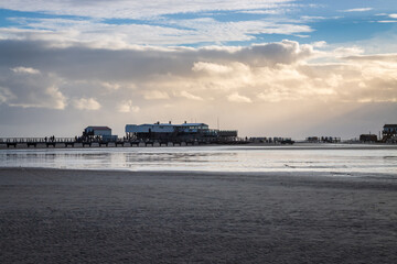 Panoramic view of stilt houses and wooden seabridge at north sea beach in Sankt Peter-Ording, Germany.