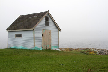 Fototapeta na wymiar Old white shed with door on a foggy day