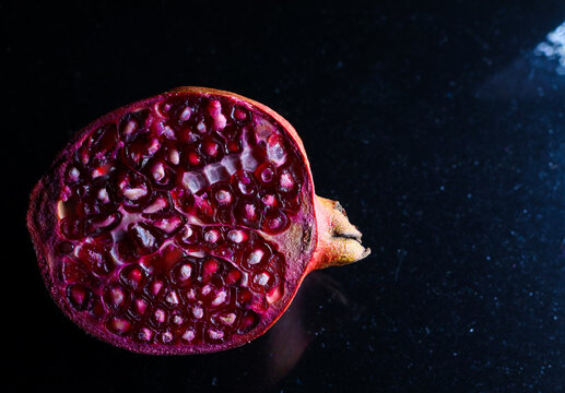 close up photo of cut pomegranate in dark background