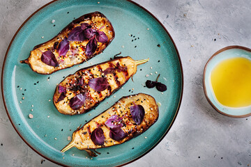 Healthy and fresh purple grilled eggplants or aubergines over grey concrete stone background, top view. Healthy Autumn vegan cooking ingredient