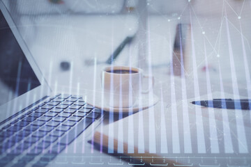 Double exposure of financial chart drawing and desktop with coffee and items on table background. Concept of forex market trading