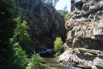Rio a correr por um vale estreito de rochas com pequenas árvores, desfiladeiro