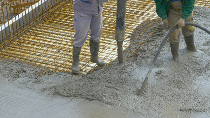 CLOSE UP: Unrecognizable team of workers pours fresh mortar over metal wiring.