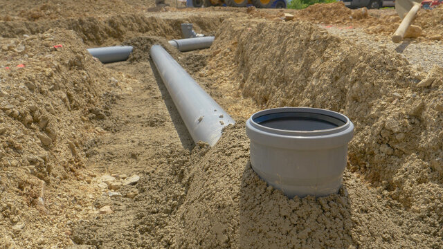 CLOSE UP: Dark grey fresh cement covers pipes of a wastewater drainage system.