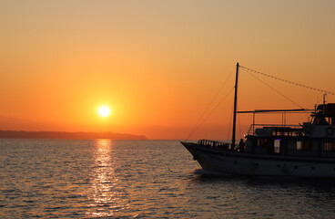 Fototapeta premium Silhouette d'un bateau traversant la mer durant un coucher de soleil à Thessalonique en Greece