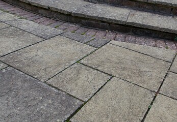 Fototapeta premium Old weather stained paving patio background with steps and bricks