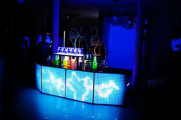 Professional barman and led light show. Silhouette of modern bartender shaking drink at night...