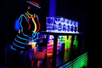 Professional barman and led light show. Silhouette of modern bartender shaking drink at night...
