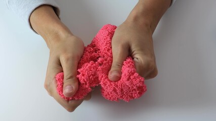 Hands crushing and crumpling pink plasticine with small balls inside, anti stress and relaxing...