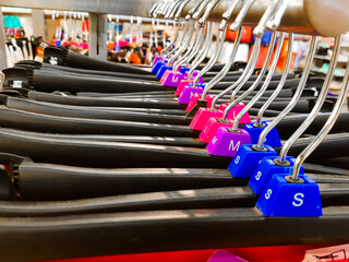 Fototapeta premium Different sized hanger with colourful dress size tags XL L M XS t shirts displayed in shop for sale