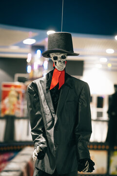 Halloween scenery. Skeleton in a black suit and hat indoors, looking at the camera. Halloween concept.