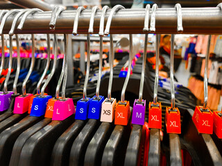 Fototapeta premium Different sized hanger with colourful dress size tags XL L M XS t shirts displayed in shop for sale