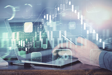 Double exposure of man's hands holding and using a digital device and forex graph drawing. Financial market concept.