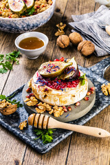 tasty healthy dish with figs fruits, nuts, honey, camembert cheese, couscous and pomegranate seeds and figs