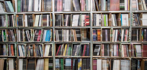 Neatly stacked records sit in rows on shelves at a warehouse ready for sale or distribution.	
