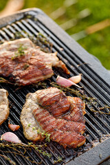 Grilled pork neck with herbs and garlic on a cast iron grill plate, close-up view