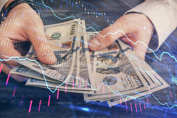 Multi exposure of financial graph drawing hologram and USA dollars bills and man hands. Analysis...