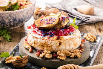 tasty healthy dish with figs fruits, nuts, honey, camembert cheese, couscous and pomegranate seeds and figs