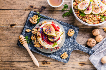 tasty healthy dish with figs fruits, nuts, honey, camembert cheese, couscous and pomegranate seeds and figs