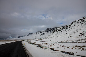 A road leading to snow covered mountains in winter in Southern Iceland