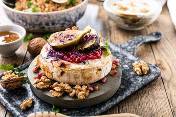 tasty healthy dish with figs fruits, nuts, honey, camembert cheese, couscous and pomegranate seeds and figs