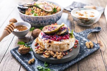 tasty healthy dish with figs fruits, nuts, honey, camembert cheese, couscous and pomegranate seeds and figs