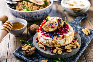 tasty healthy dish with figs fruits, nuts, honey, camembert cheese, couscous and pomegranate seeds and figs