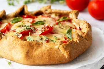 Homemade tomato tart or galette. Whole wheat rustic pie with tomatoes, cheeseand herbs. Healthy food concept.