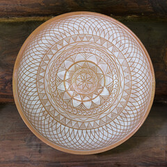 Decorative ceramic painted plate on wooden wall.