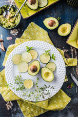 top view of organic raw green avocados sliced in halves with toasts on rustic table